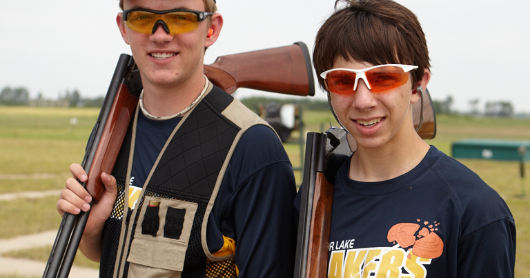 Two youths with rifles posing for a photo.